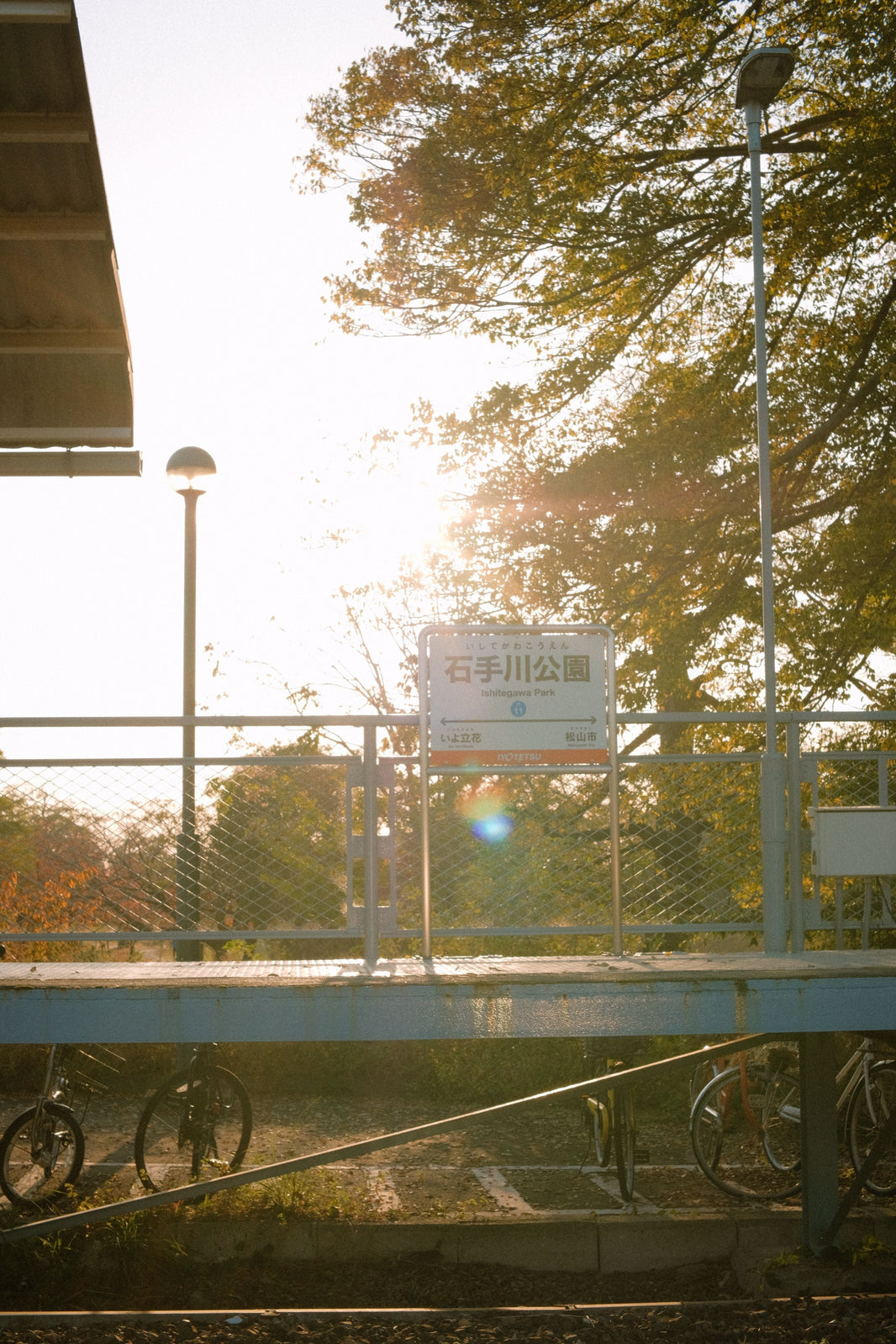 Vélos stationnés près du quai d’une gare, éclairés par le soleil.
