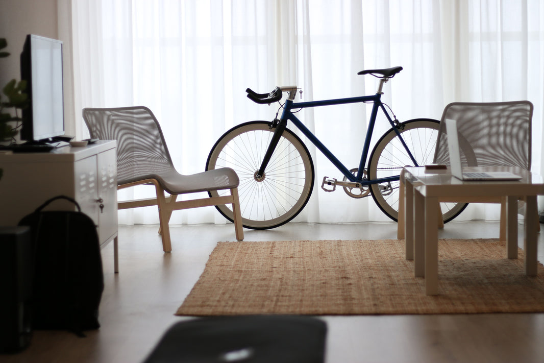 Vélo rangé dans un salon près d’une fenêtre.